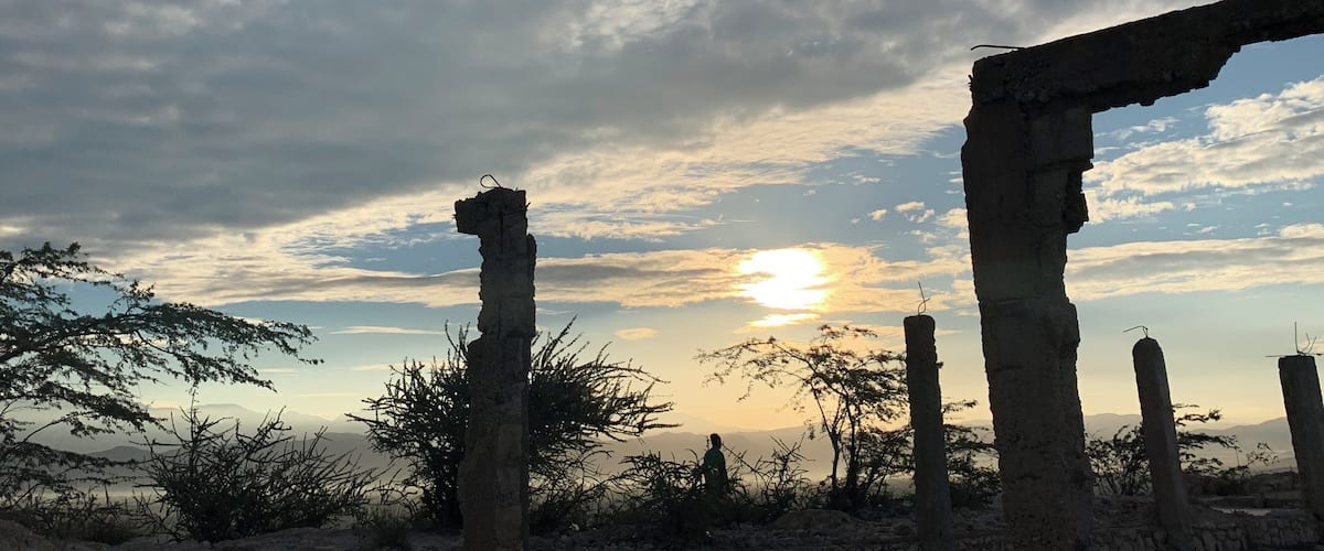 Ancient ruins with columns and a sunset in the background.