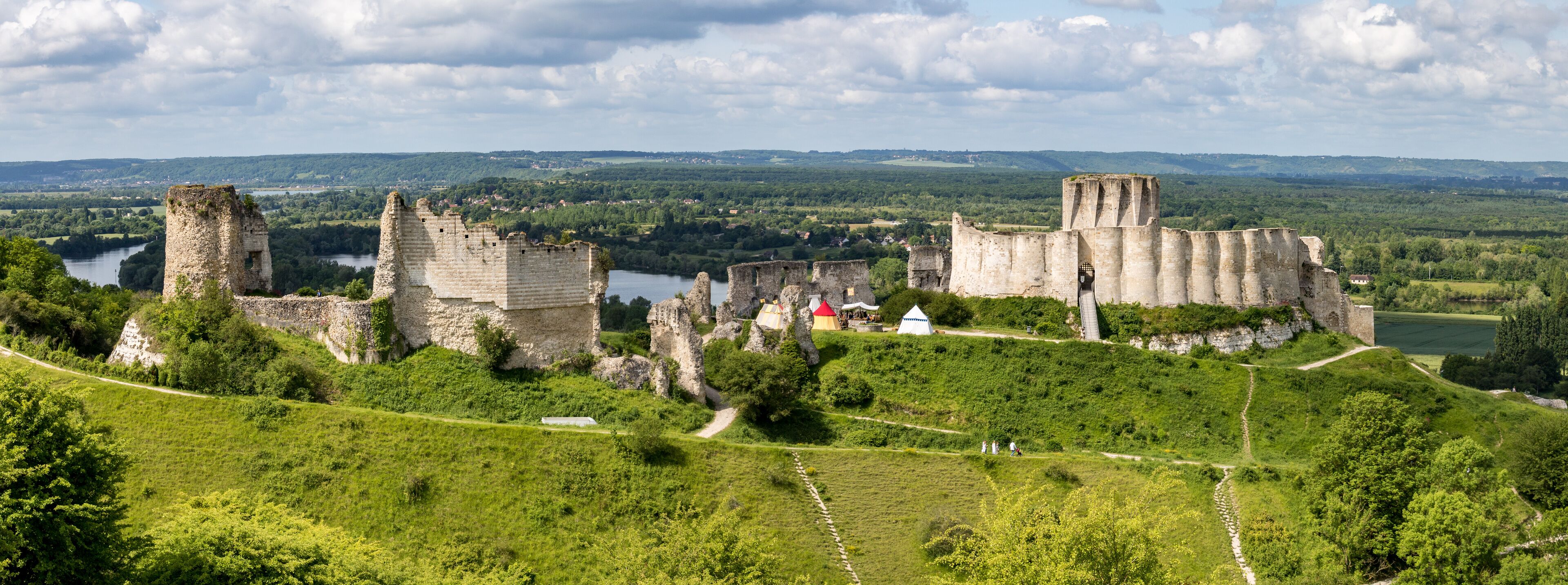 A historic castle surrounded by lush green hills and a river.