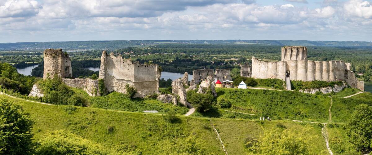 A historic castle surrounded by lush green hills and a river.