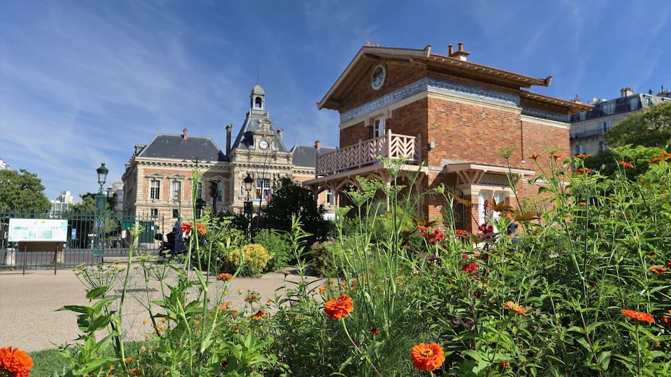 A historic building with a clock tower, surrounded by vibrant flowers and greenery.