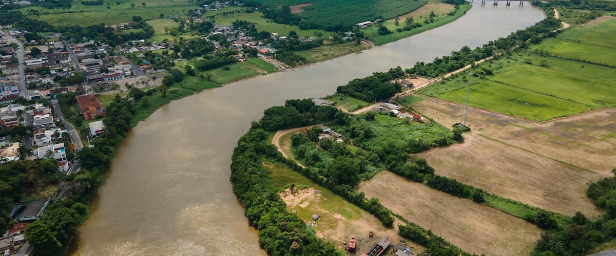 A river winding through a town with a bridge in the distance.