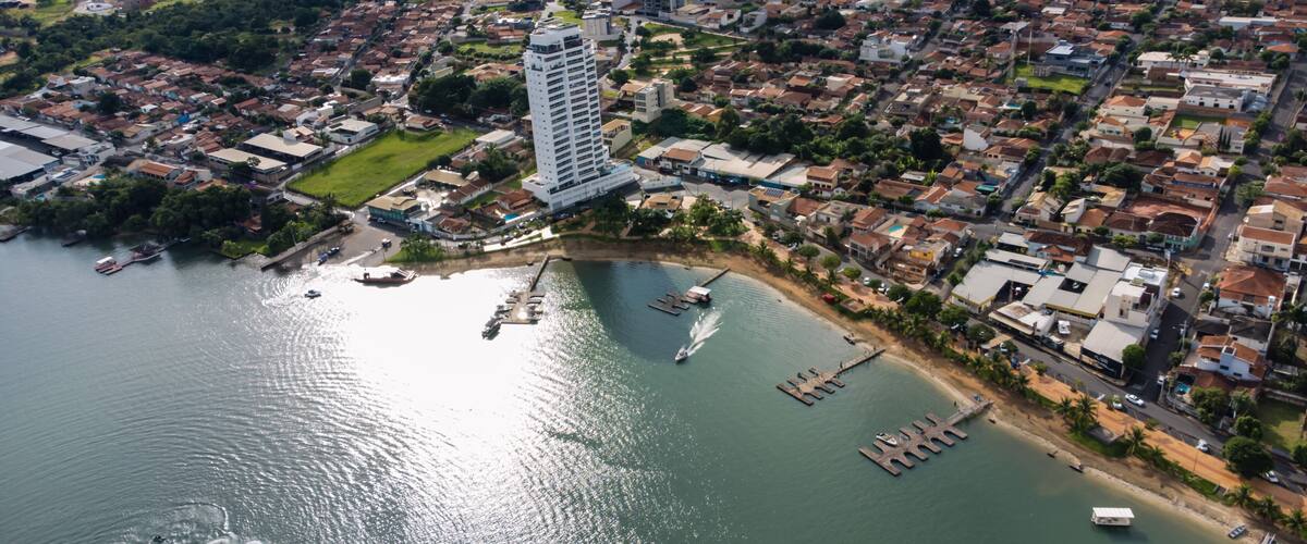 An aerial view of a coastal city with a prominent high-rise building, a marina with boats, and residential areas.