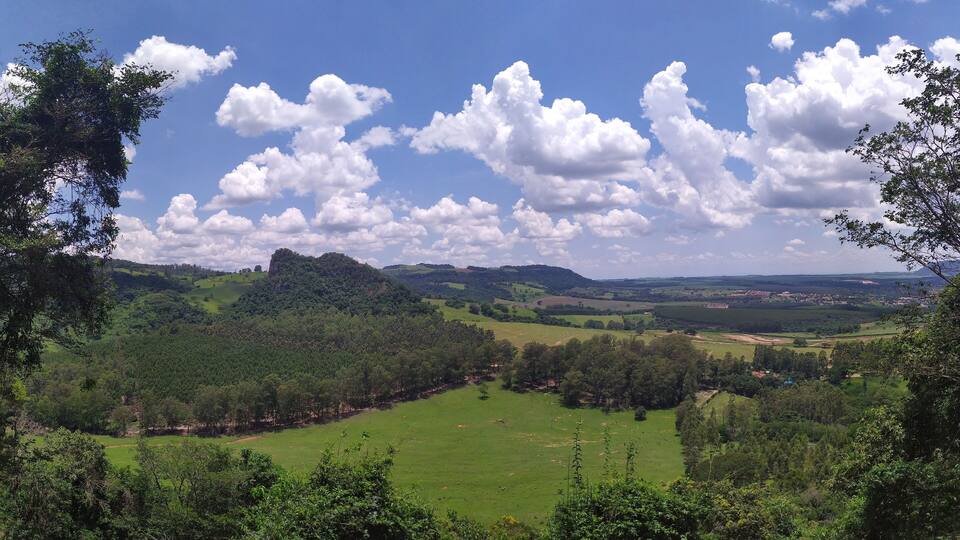A lush green valley with rolling hills, a clear blue sky, and scattered clouds.