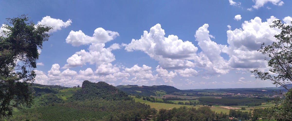A lush green valley with rolling hills, a clear blue sky, and scattered clouds.
