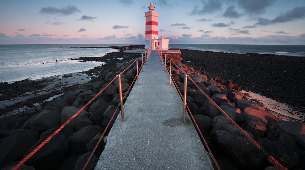 Old lighthouse in Gardur, Keflavik, Iceland. Cloudy Sky and choppy sea. Beautiful sunset scene
