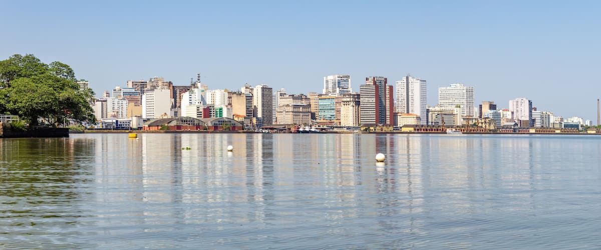 A city skyline with tall buildings reflected in calm water.