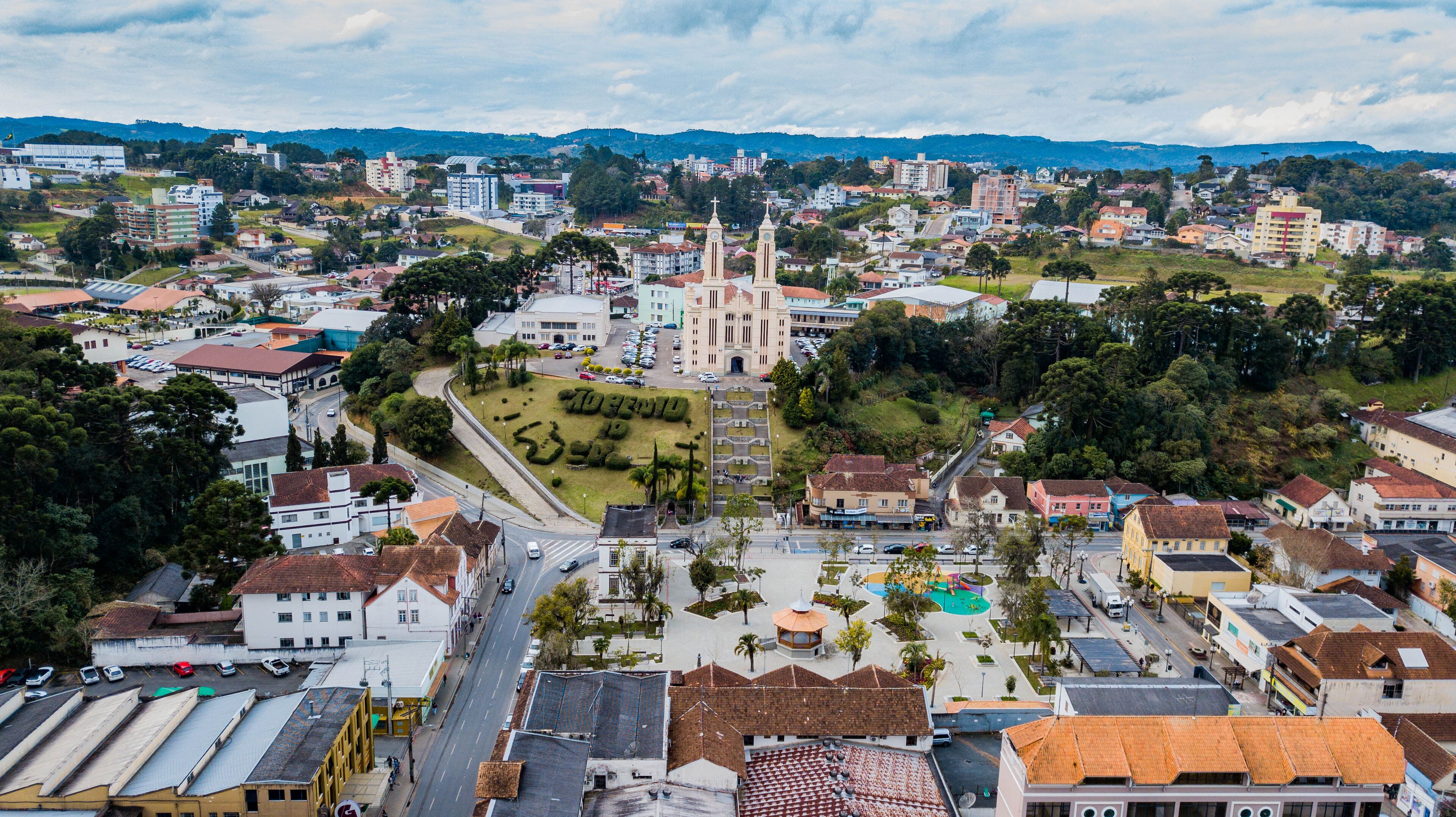 A cityscape with a prominent church, residential buildings, and a hilly landscape in the background.