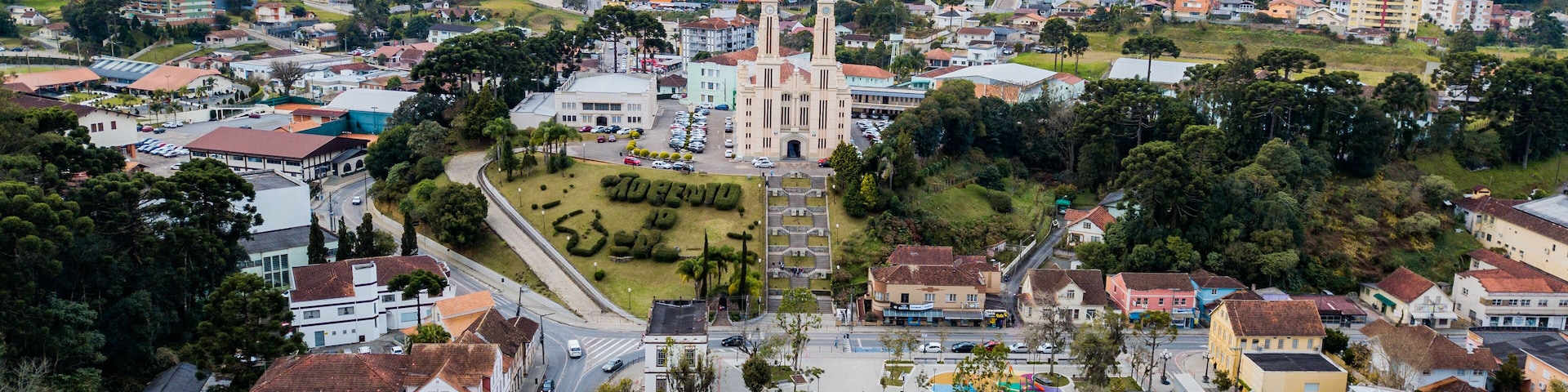 A cityscape with a prominent church, residential buildings, and a hilly landscape in the background.