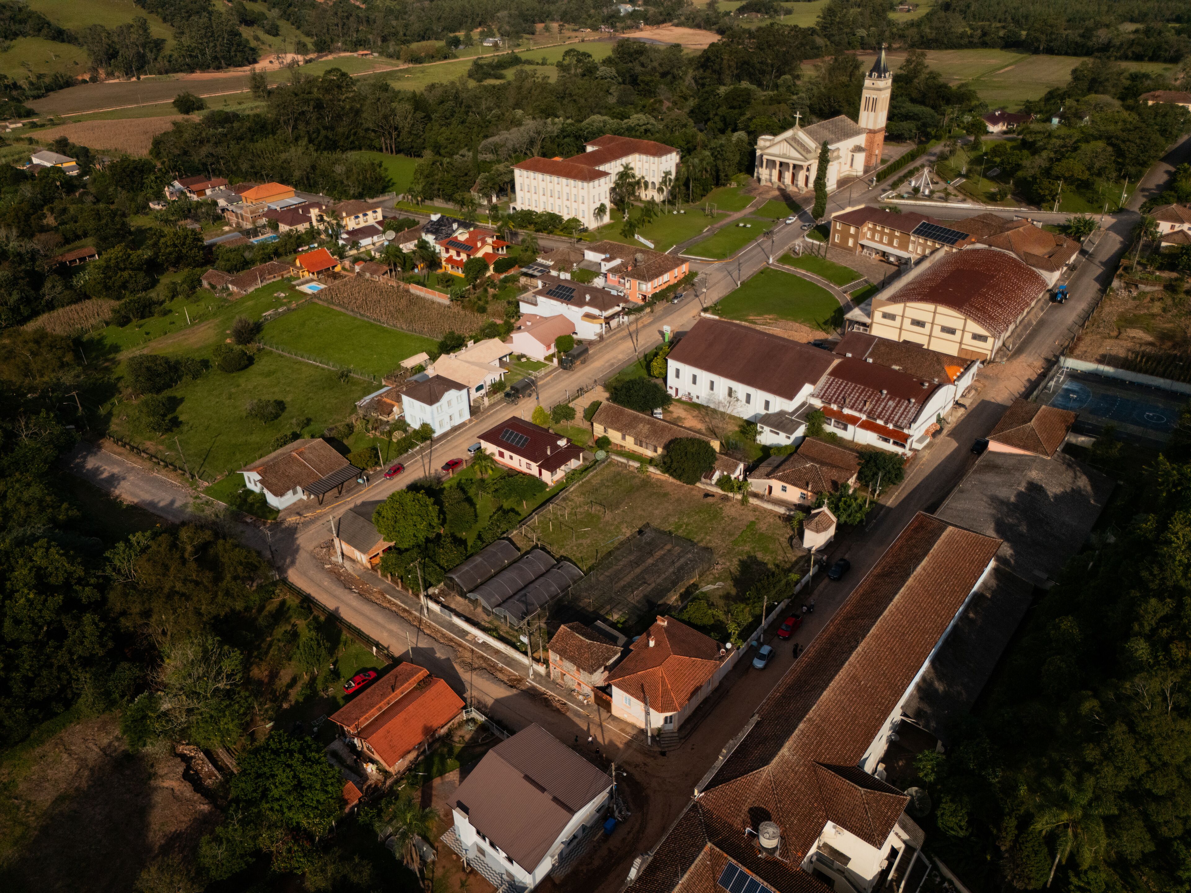 An aerial view of a town with a prominent church, residential houses, and surrounding greenery.