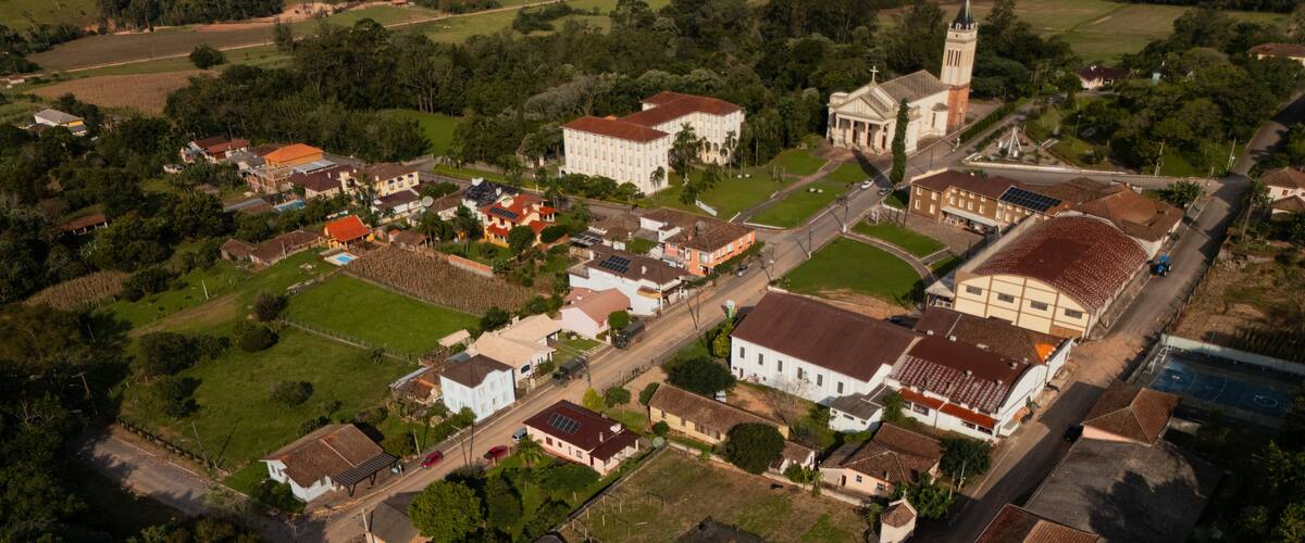 An aerial view of a town with a prominent church, residential houses, and surrounding greenery.