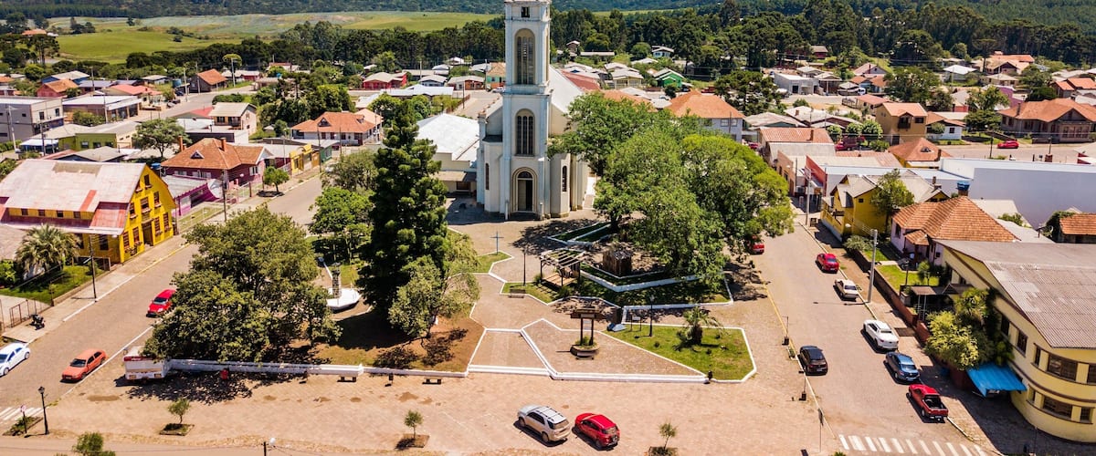 A town with a prominent church featuring a bell tower, surrounded by residential buildings and lush greenery.