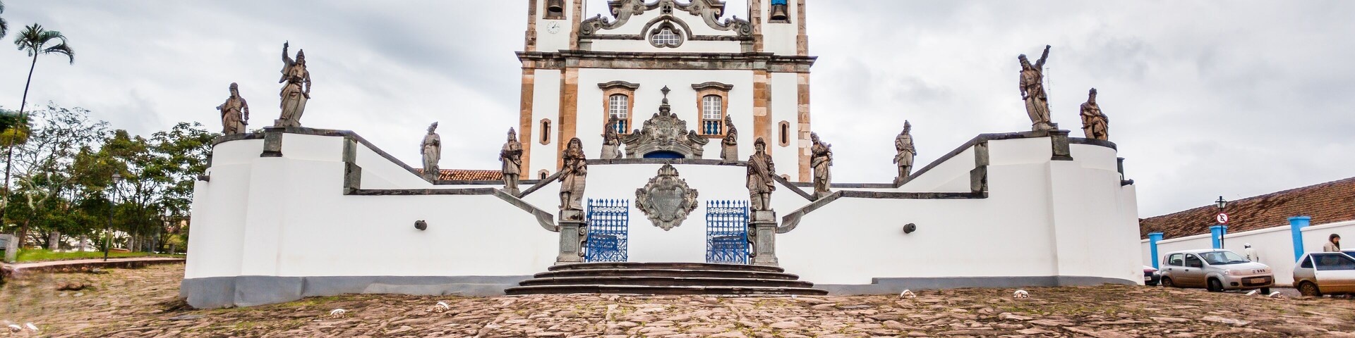 Una iglesia histórica con dos torres, estatuas y una plaza adoquinada.