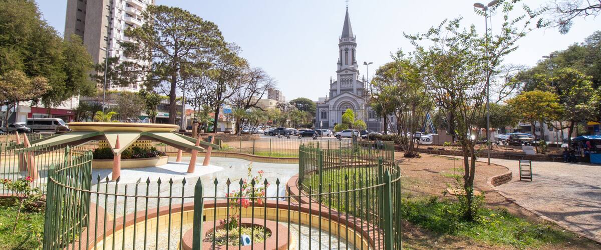 A park with a fountain, a church, and a tall building in the background.