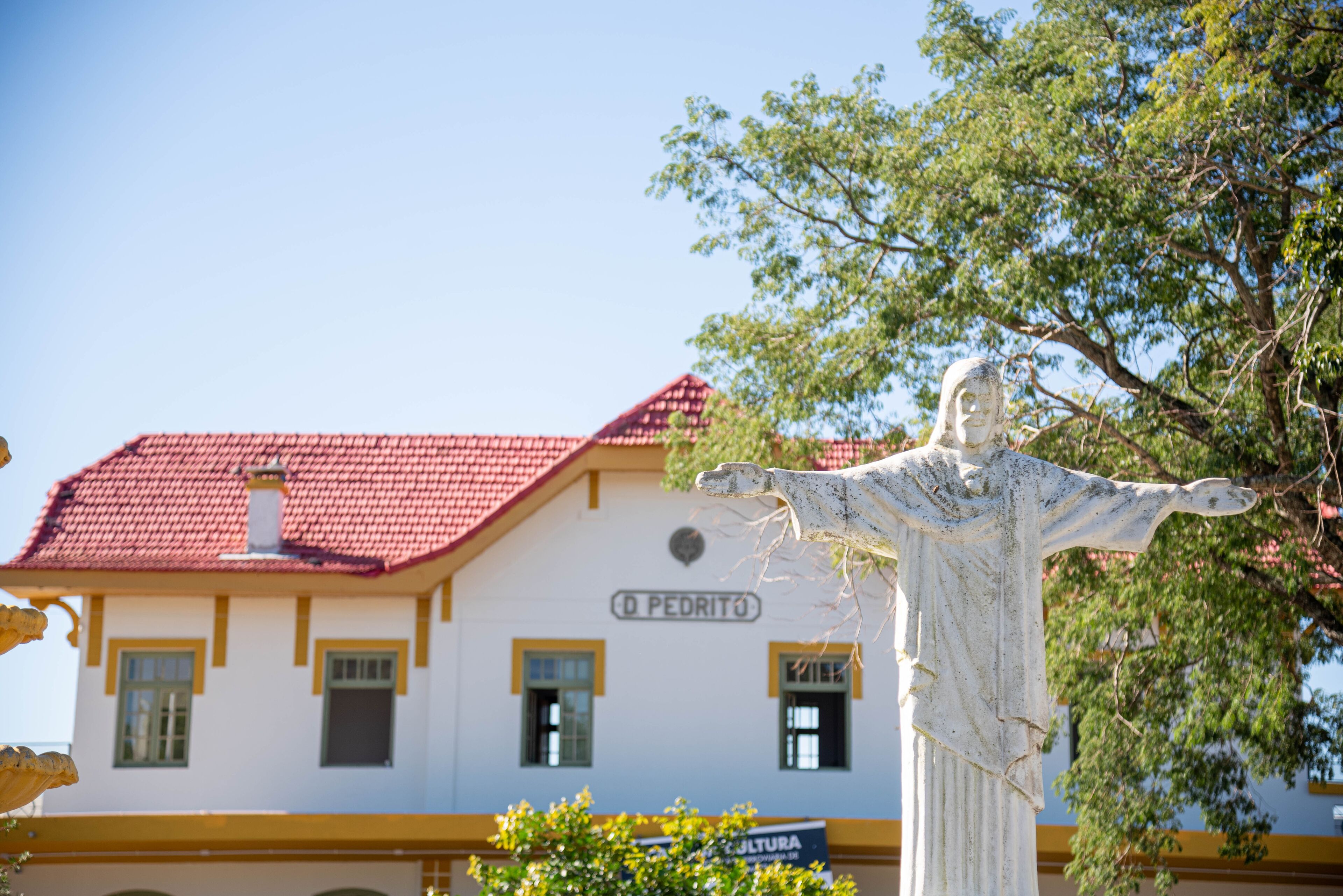 A statue in front of a building with a red roof and a sign that reads "O PEDRITO".