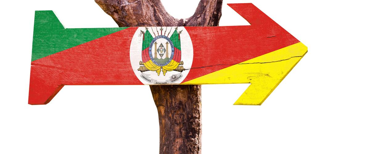 A wooden signpost with a flag and a coat of arms.