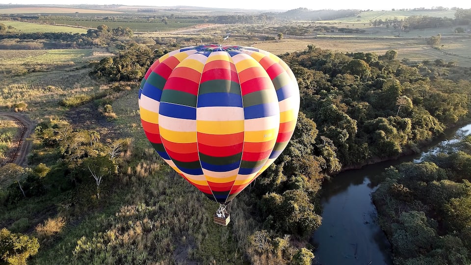 A colorful hot air balloon over a lush landscape with a river.