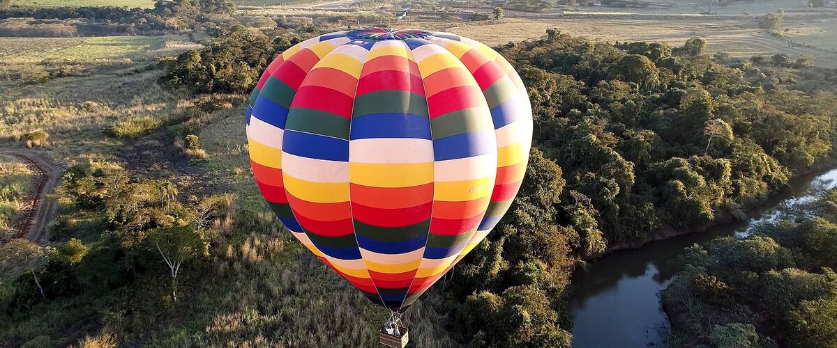 A colorful hot air balloon over a lush landscape with a river.