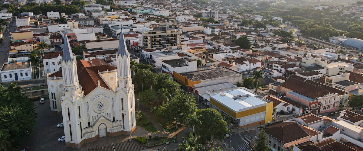 A cityscape with a prominent church featuring a tall spire and a clock tower, surrounded by residential buildings and greenery.