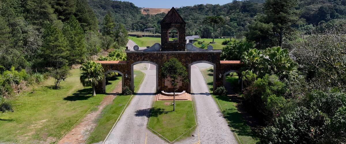 A stone archway with a tower, surrounded by lush greenery and hills.