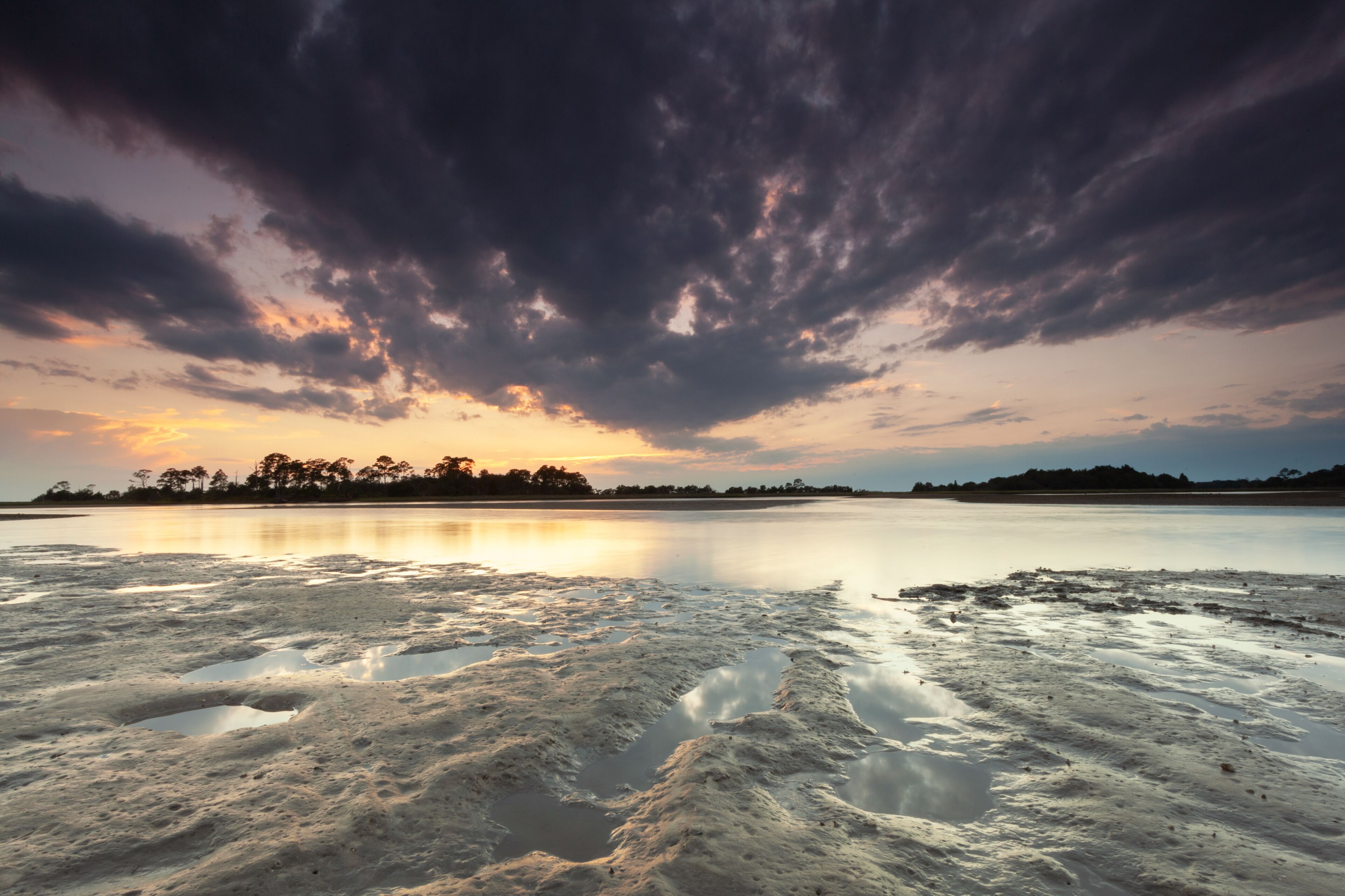 A calm lake at sunset with a cloudy sky.