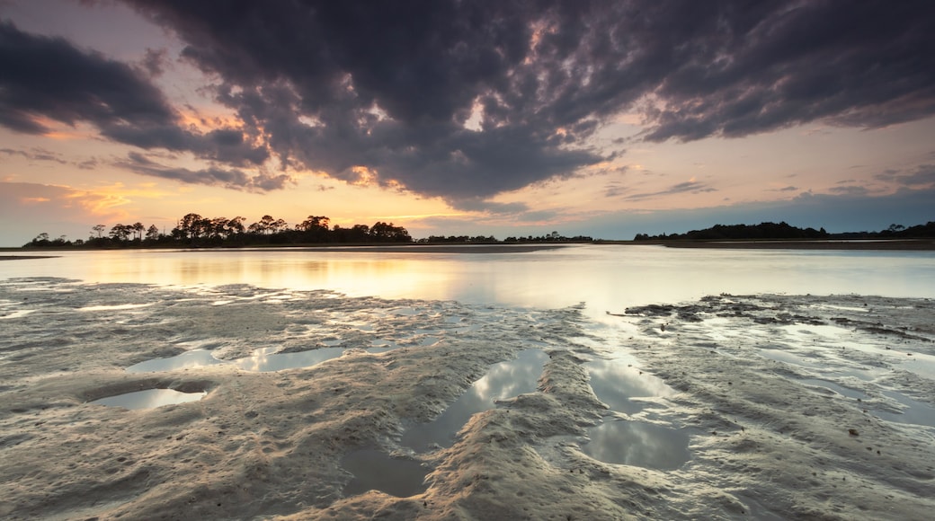 A calm lake at sunset with a cloudy sky.