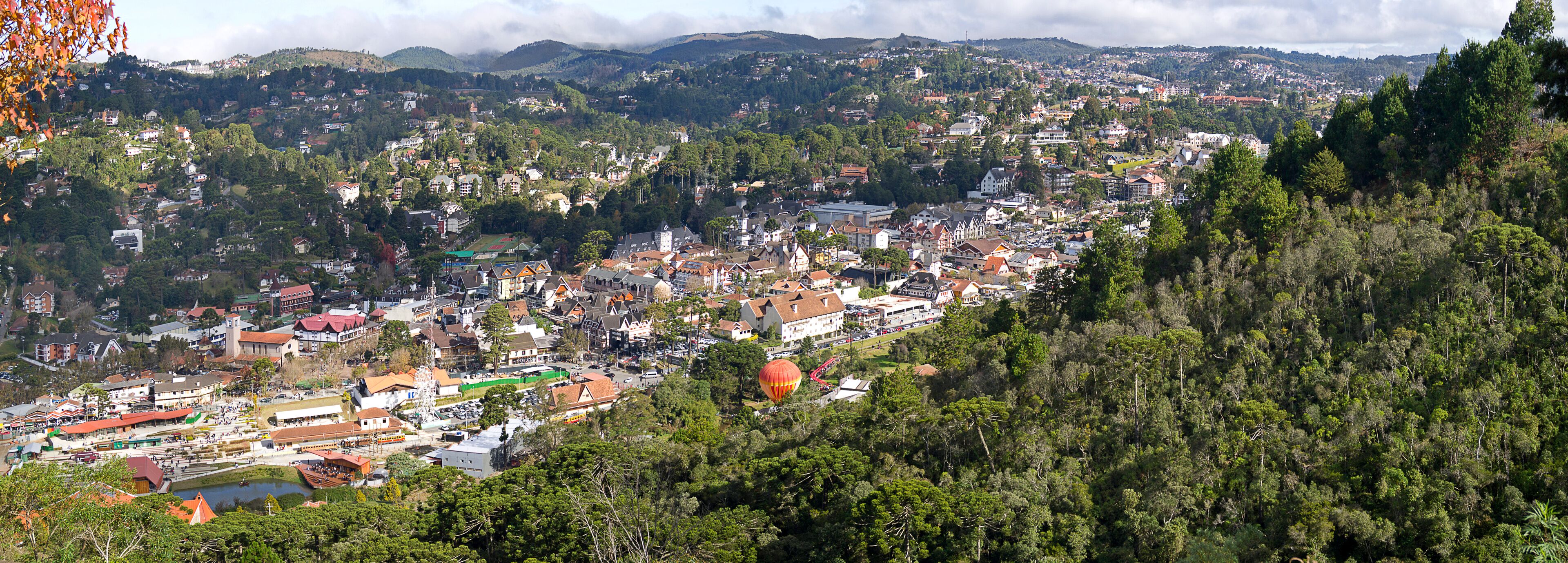 A town nestled in a valley with a river, surrounded by hills and dense forests.
