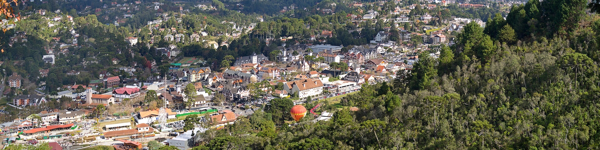 A town nestled in a valley with a river, surrounded by hills and dense forests.