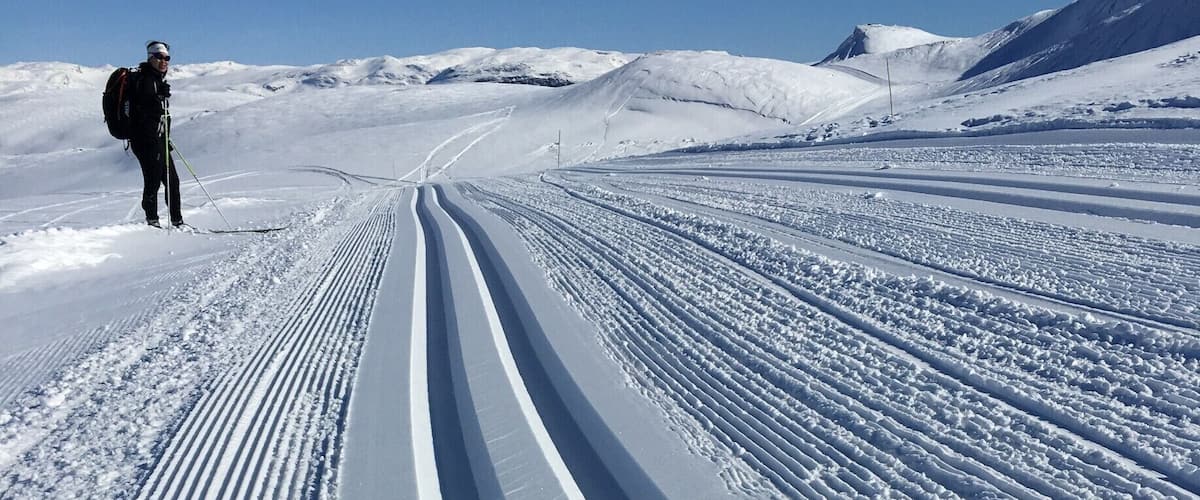 A snowy mountain landscape with a person skiing.