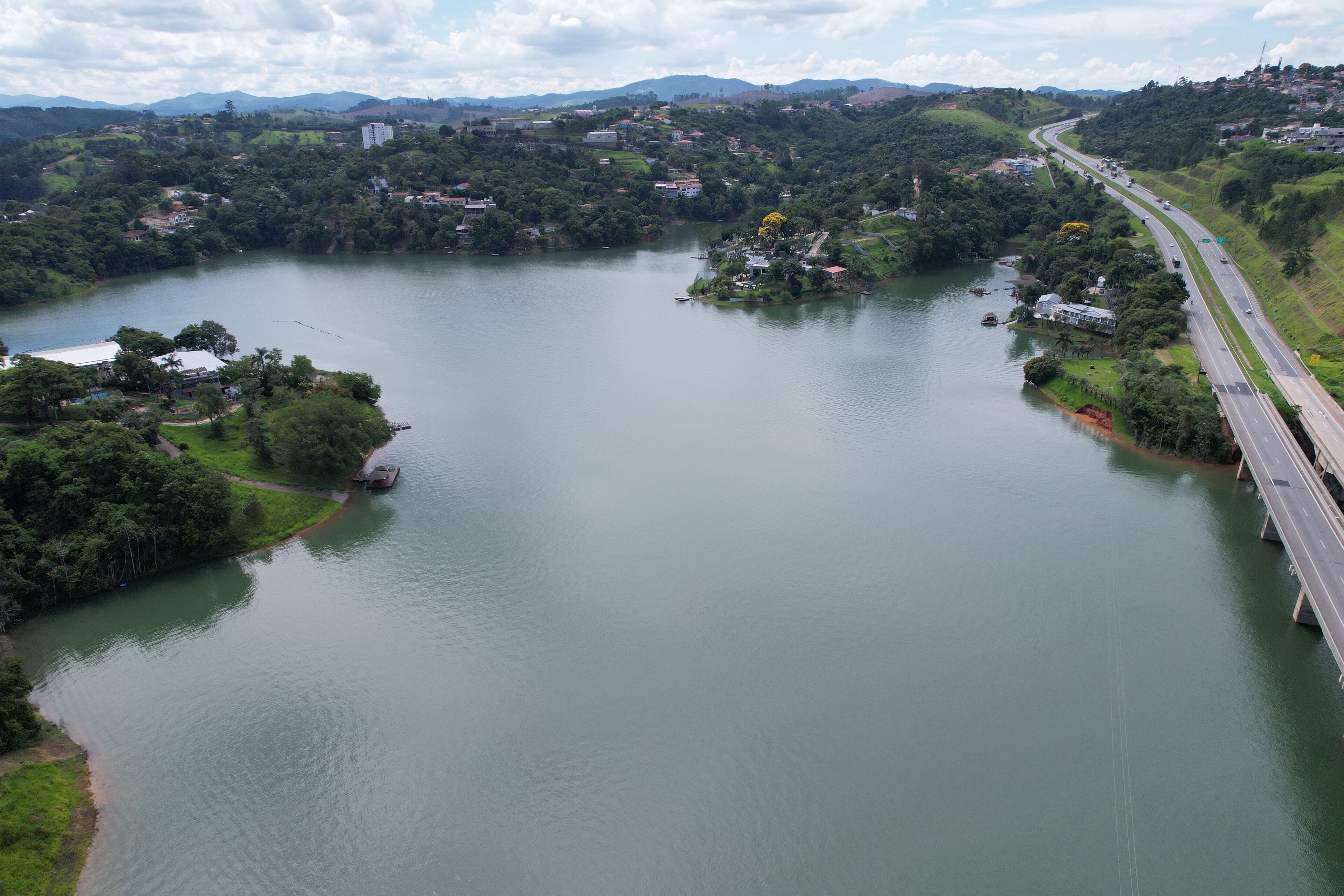 A river with a bridge, surrounded by greenery and hills.