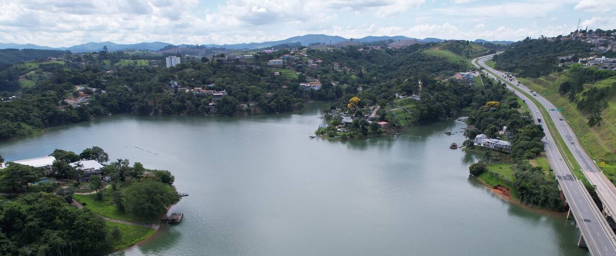 A river with a bridge, surrounded by greenery and hills.