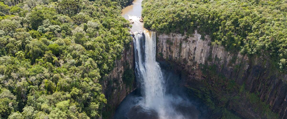 A waterfall cascading down a steep cliff surrounded by dense forest.
