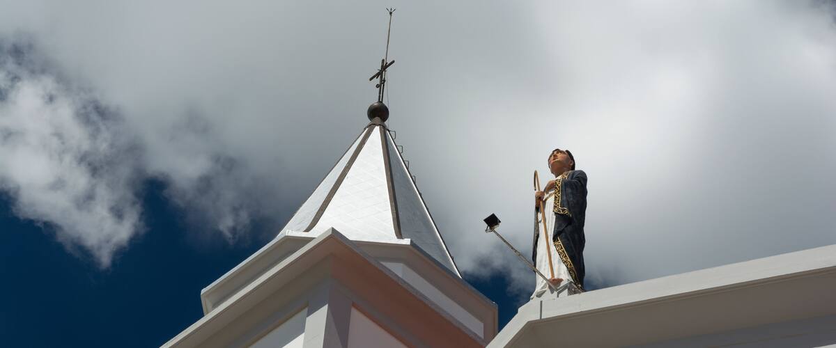 A church steeple with a clock and a statue.