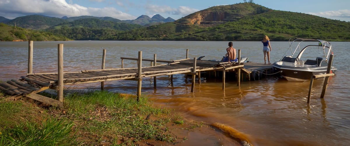A wooden dock extending into a calm lake with mountains in the background.