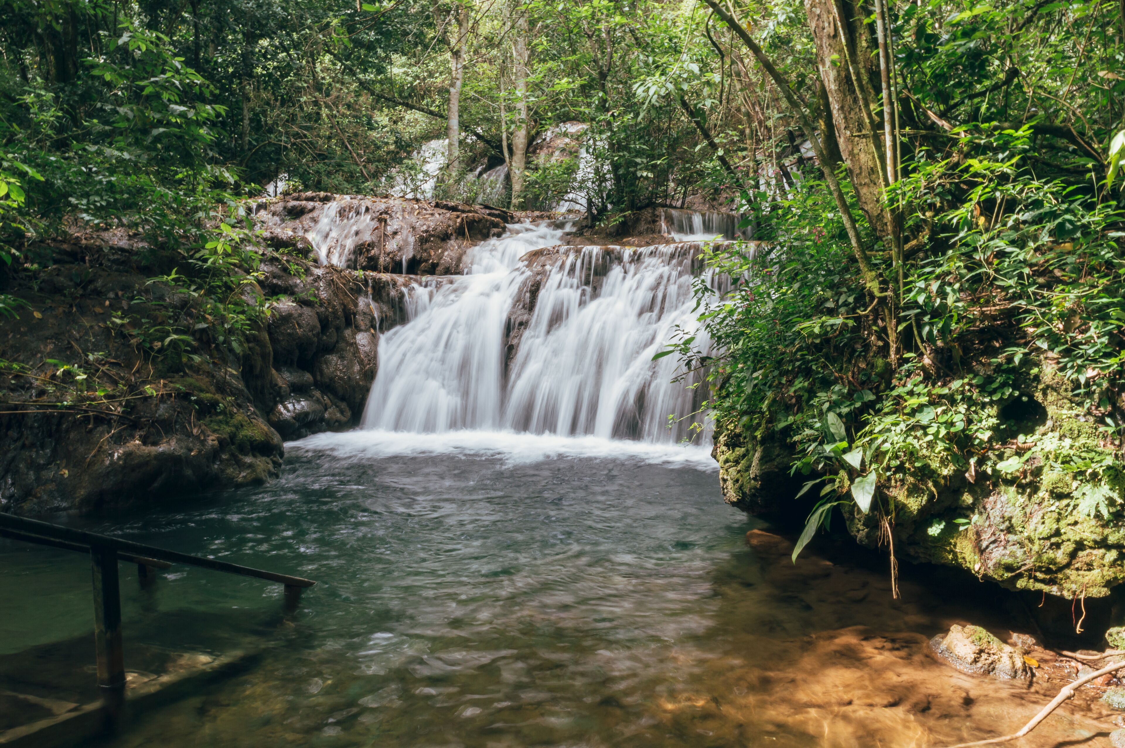 A waterfall in a forested area with a viewing platform.