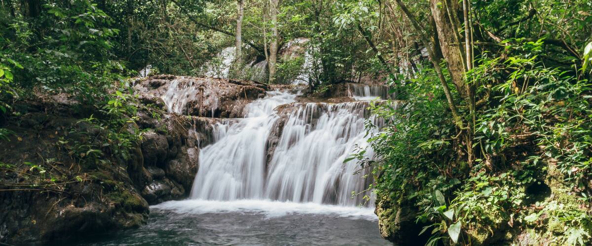 A waterfall in a forested area with a viewing platform.