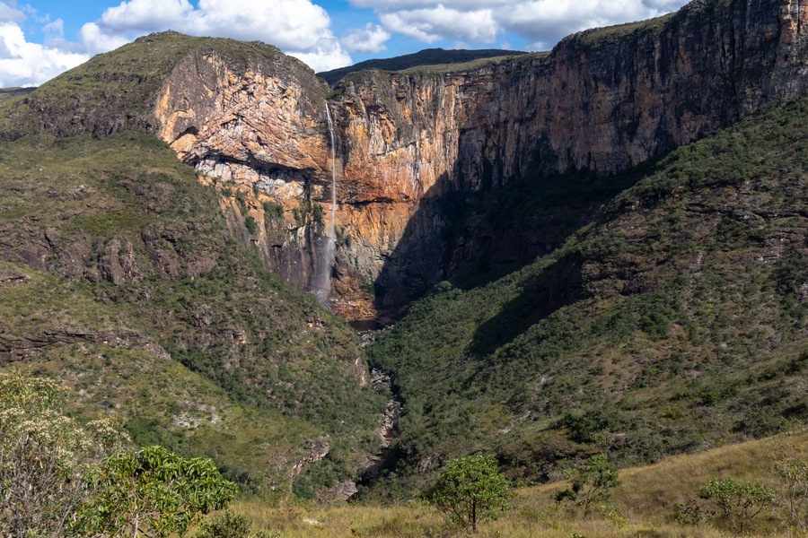 Cañón con cascada, acantilados empinados y vegetación circundante.