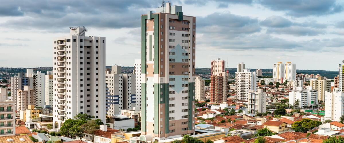 A cityscape with a mix of high-rise buildings and traditional houses, under a cloudy sky.