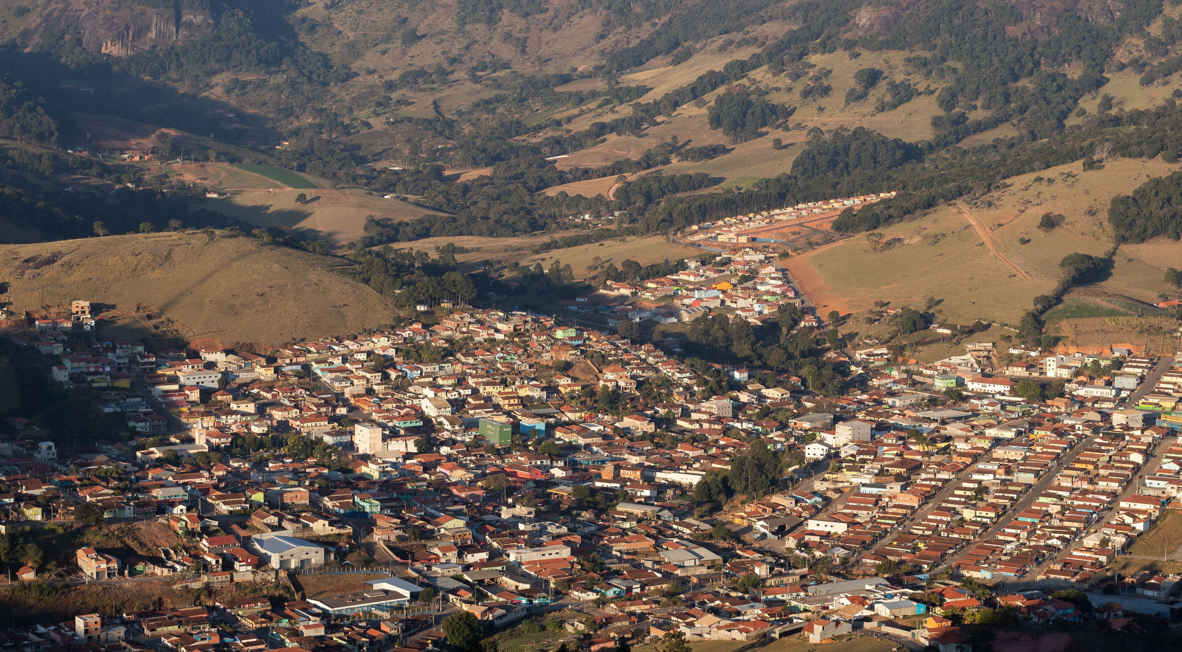 A densely populated town nestled in a valley with surrounding hills and sparse vegetation.