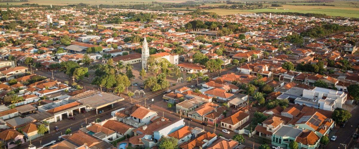 A densely populated town with red-roofed houses, a prominent church tower, and a large open field in the distance.