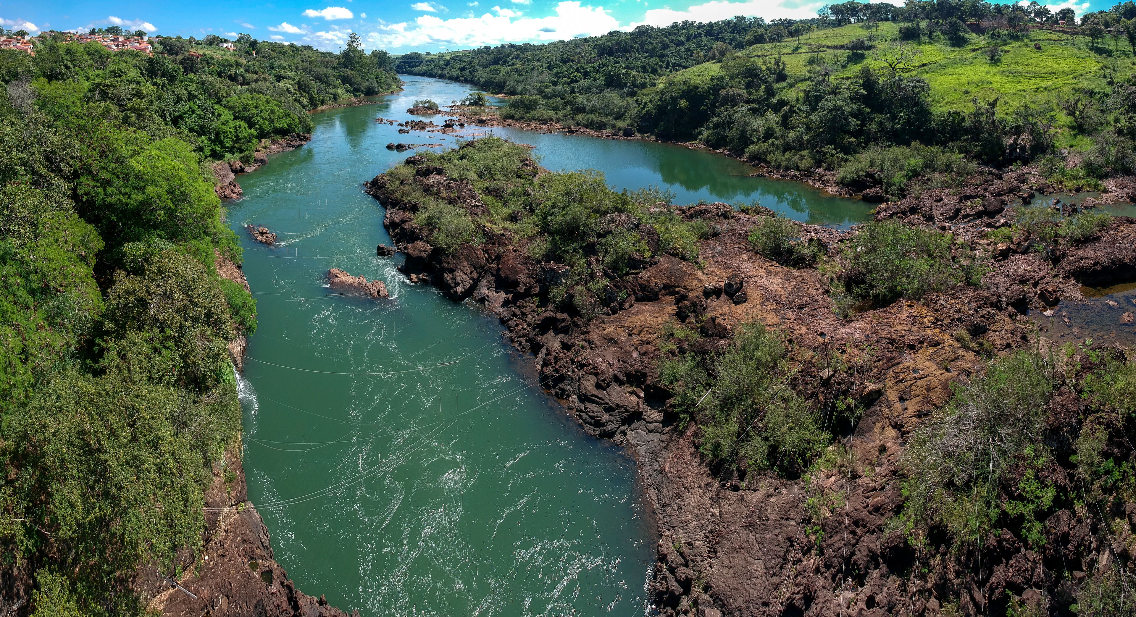 A river winding through a lush valley with dense greenery and rocky outcrops.