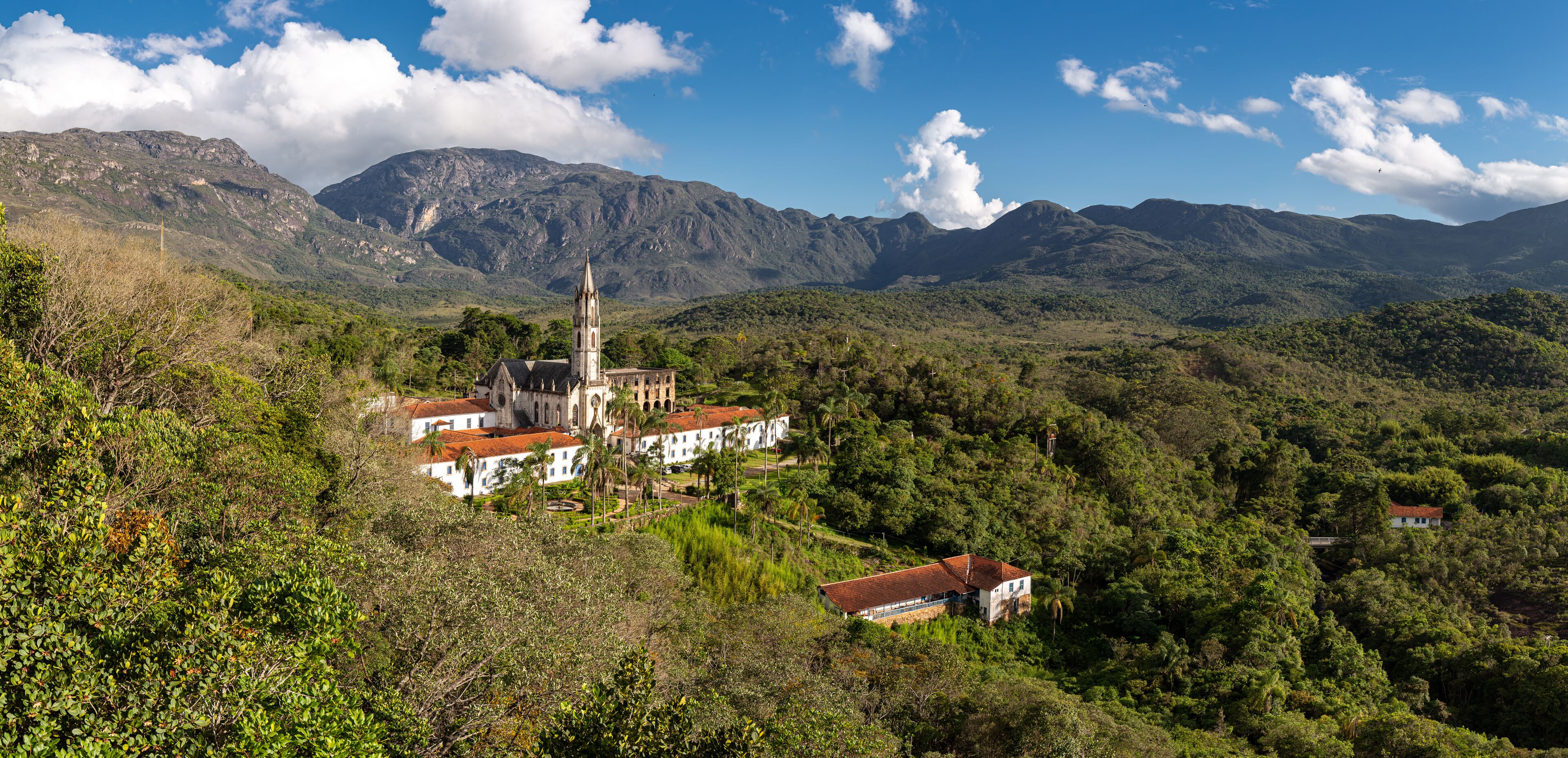 A church with a tall bell tower surrounded by lush green hills and mountains.