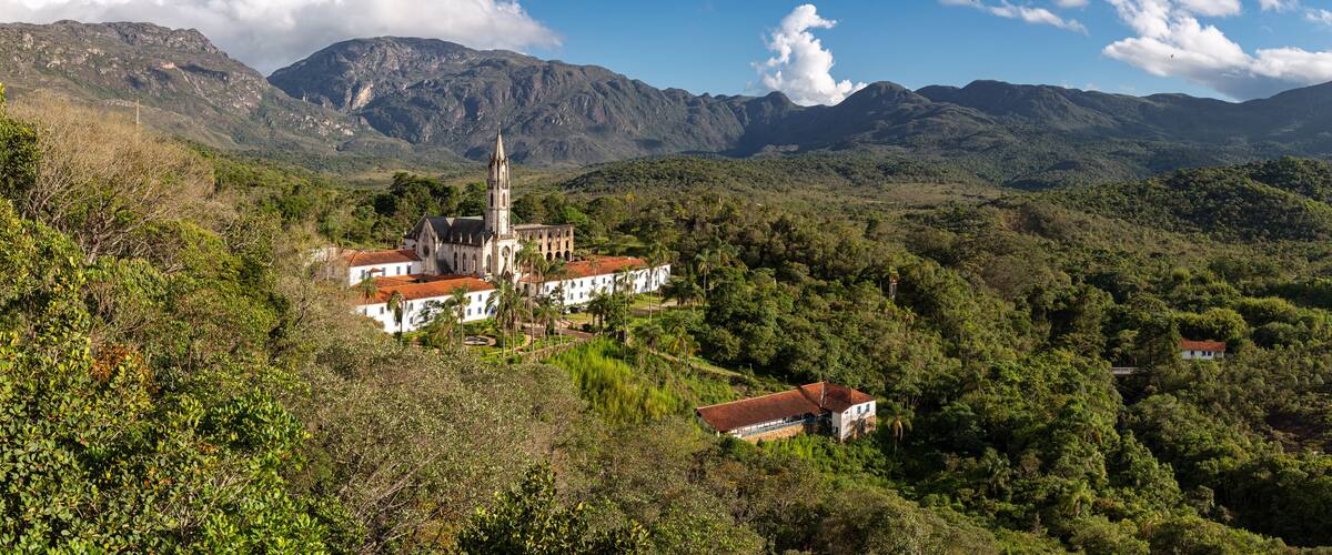 A church with a tall bell tower surrounded by lush green hills and mountains.
