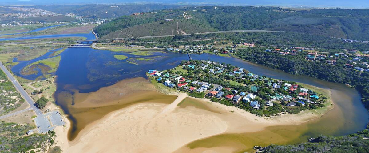 An aerial view of a coastal area with a river, a bridge, and a residential community.