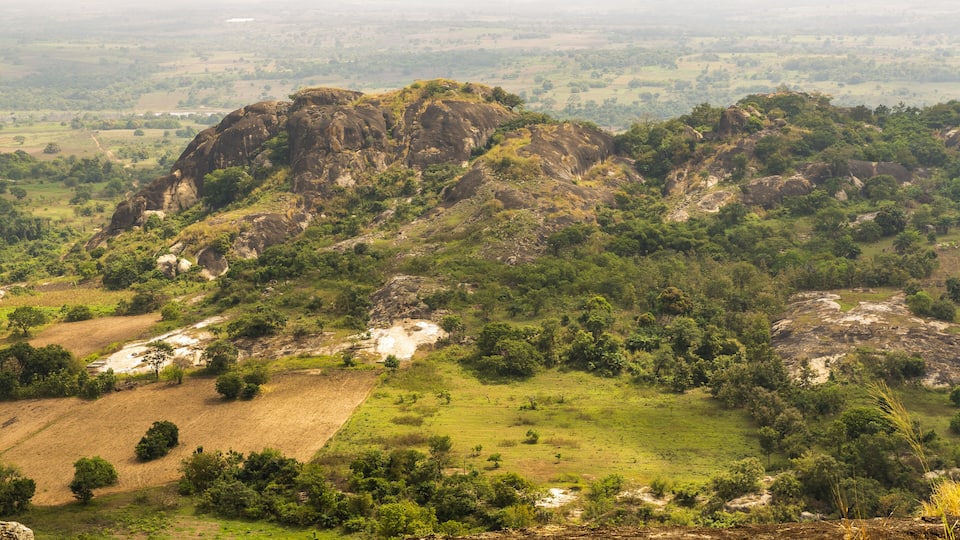 A mountainous landscape with green fields and rocky outcrops.