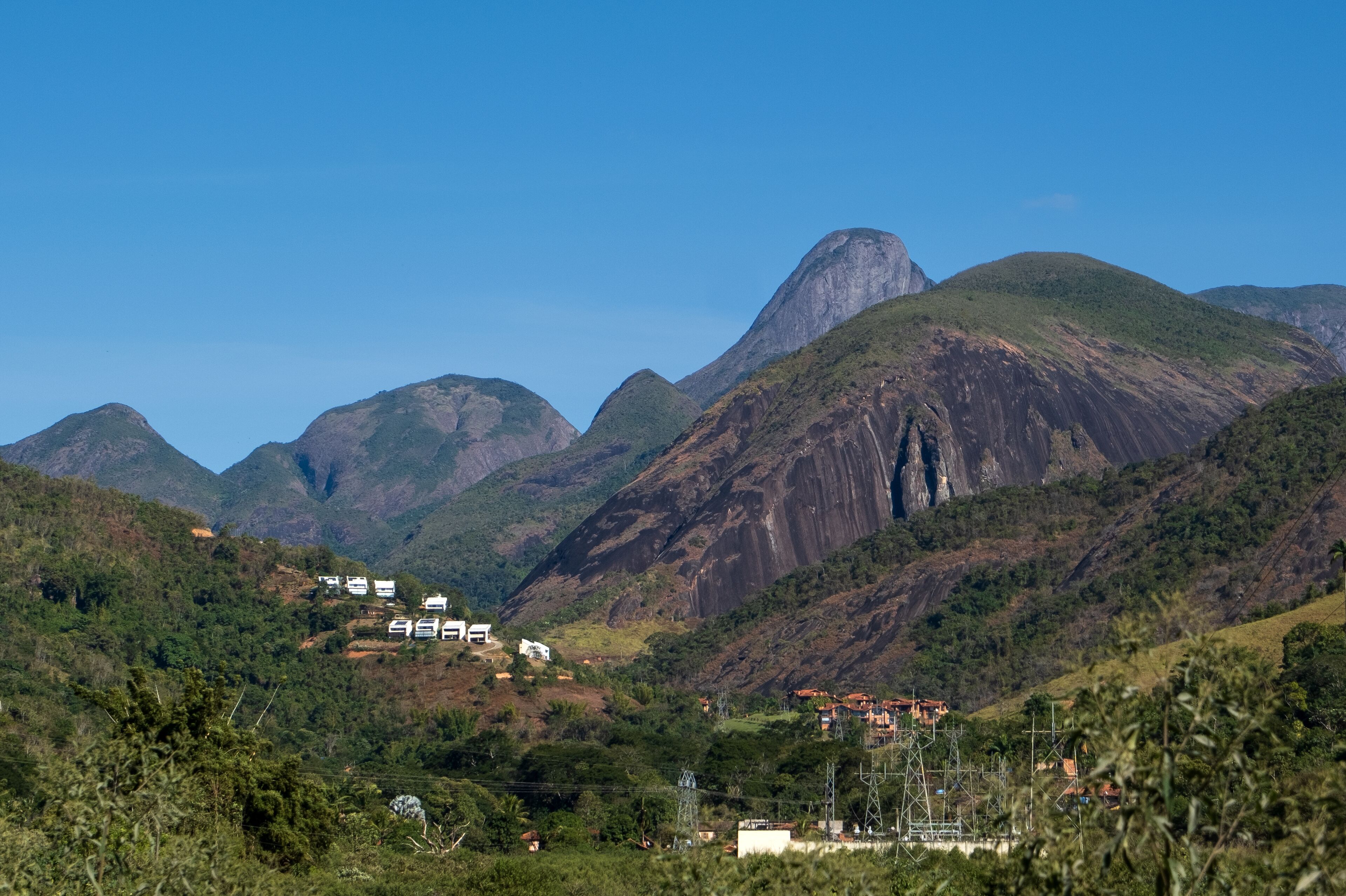 A mountainous landscape with a prominent peak, lush greenery, and scattered buildings.