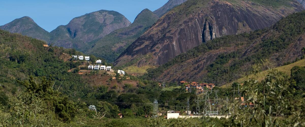 A mountainous landscape with a prominent peak, lush greenery, and scattered buildings.