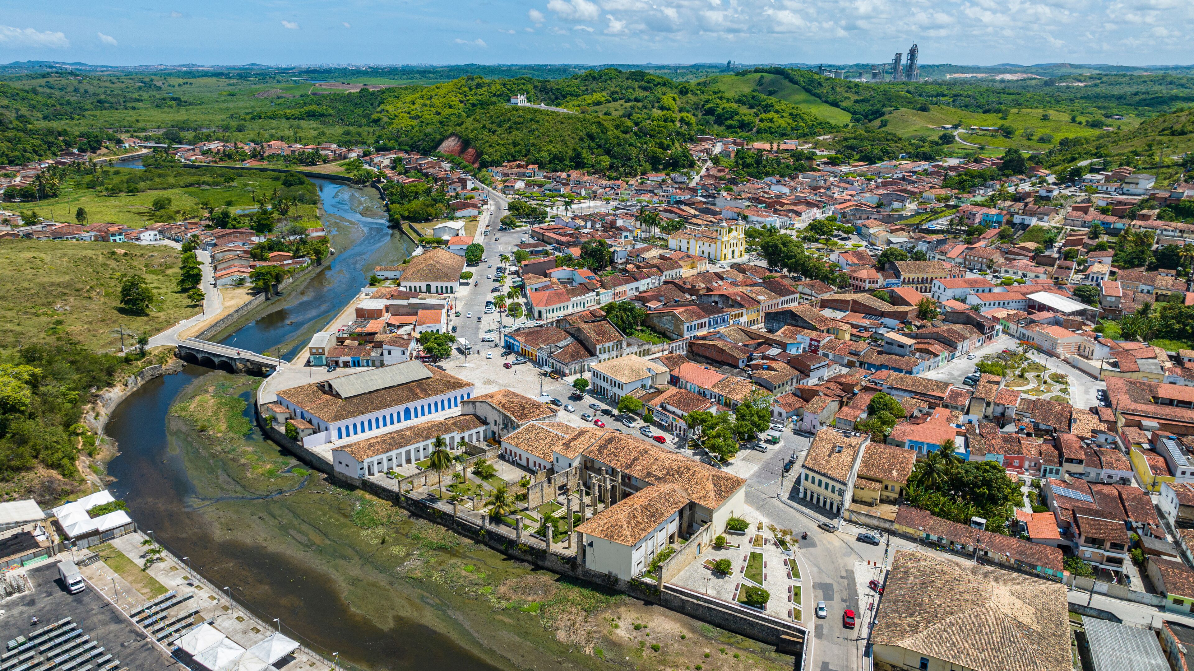 A river winding through a town with red-roofed buildings and a bridge.