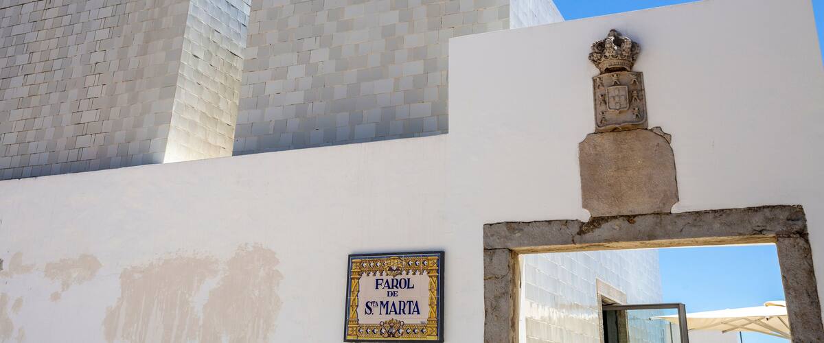 A building with a tiled facade, a red balcony, and a sign reading "Farol de St. Marta".