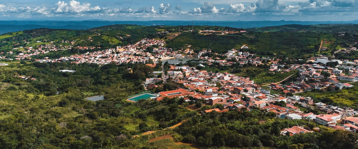 A coastal town with red-roofed buildings, a beach, and surrounding hills.