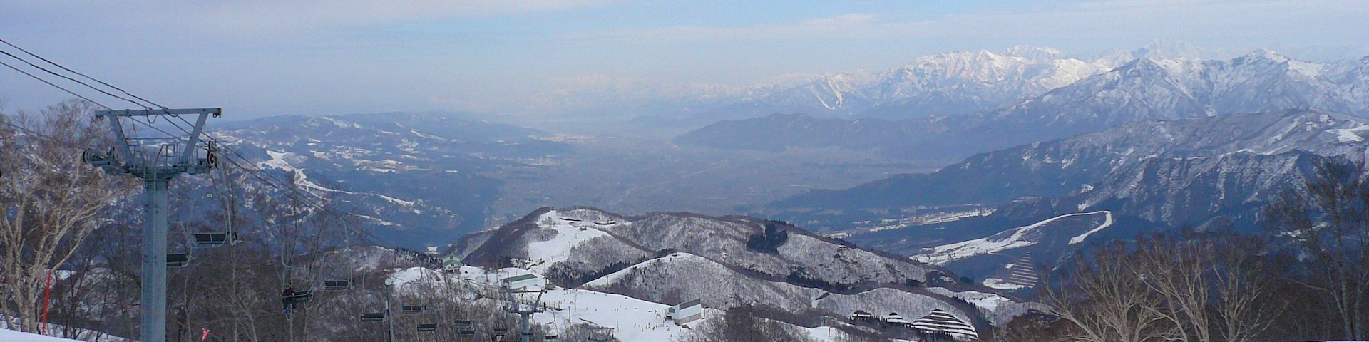 Cordilheira nevada com teleféricos e céu limpo.